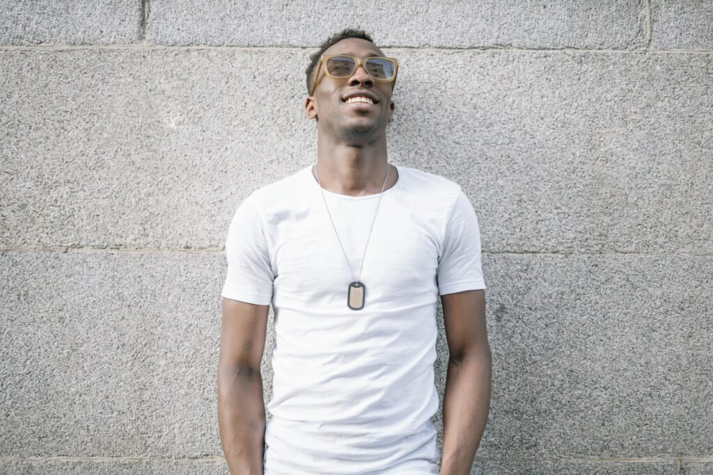 African man wearing white shirt and sunglasses posing.